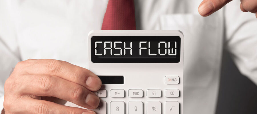 Ein Mann im Anzug hält einen Taschenrechner vor sich hoch. Auf diesem steht die Worte, Cash Flow.