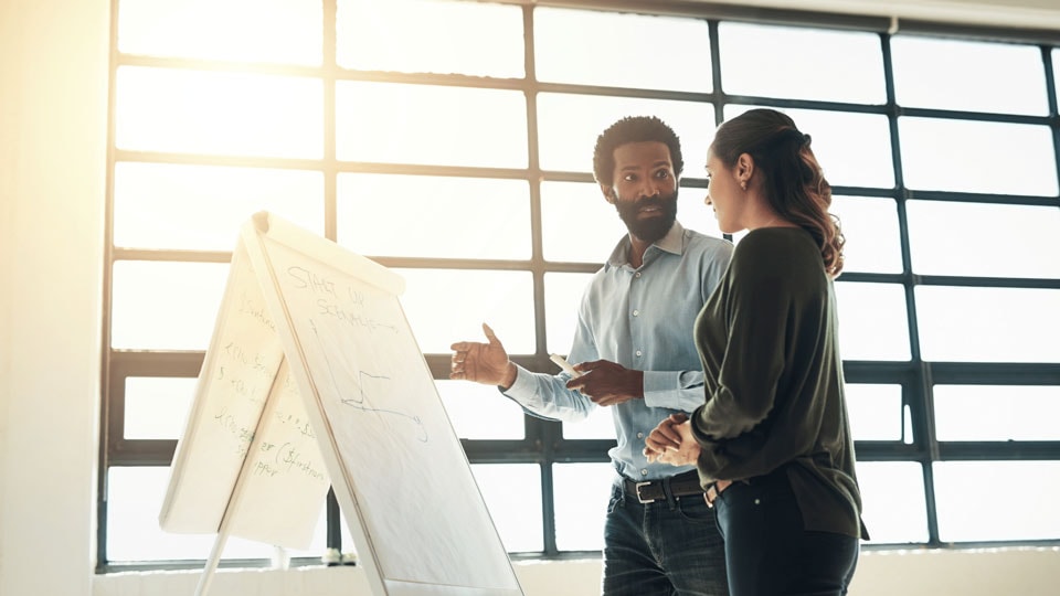 Zwei Personen stehen vor einem Flipchart und besprechen strategische Inhalte – Symbolbild für Szenarioanalyse und Zukunftsplanung.